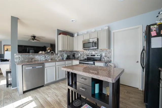 a kitchen with kitchen island granite countertop a sink cabinets and refrigerator