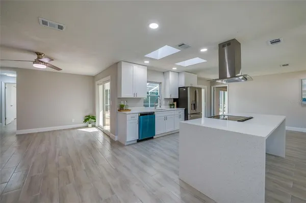 a kitchen with kitchen island a large counter space a sink appliances and cabinets