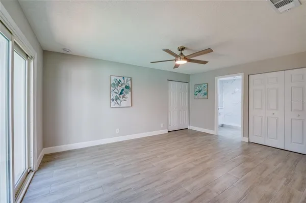 an empty room with wooden floor and ceiling fan