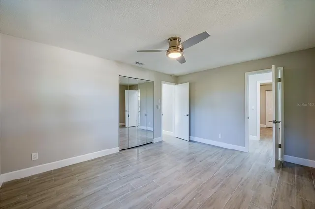 a view of an empty room with a window and wooden floor