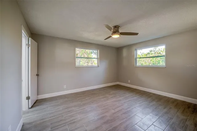 a view of an empty room with wooden floor and a window