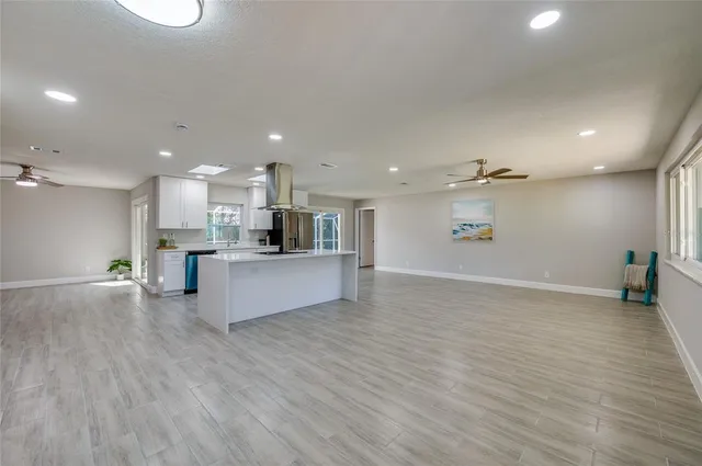 a view of a big room with wooden floor and a kitchen