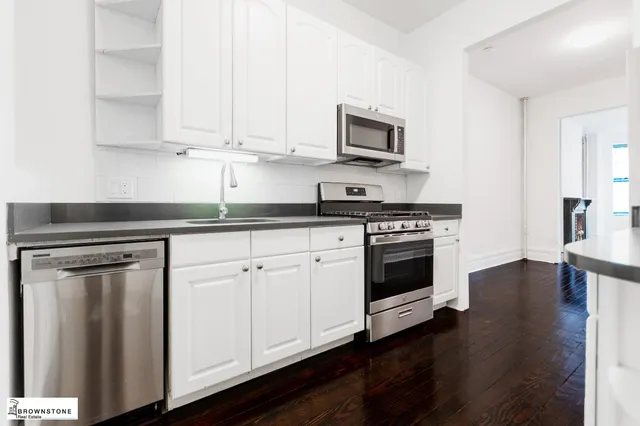 an empty room with wooden floor fireplace and windows