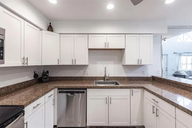 a kitchen with granite countertop white cabinets and white appliances