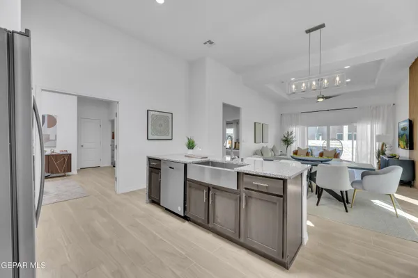 a room with kitchen island granite countertop lots of wooden furniture a sink stainless steel appliances and cabinets