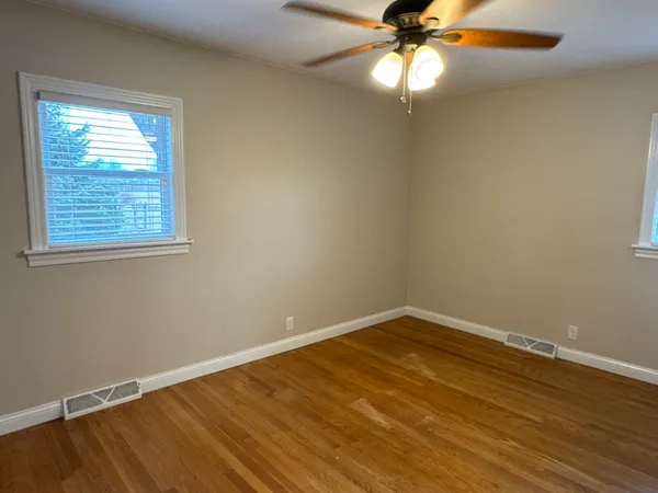 an empty room with a window and chandelier fan