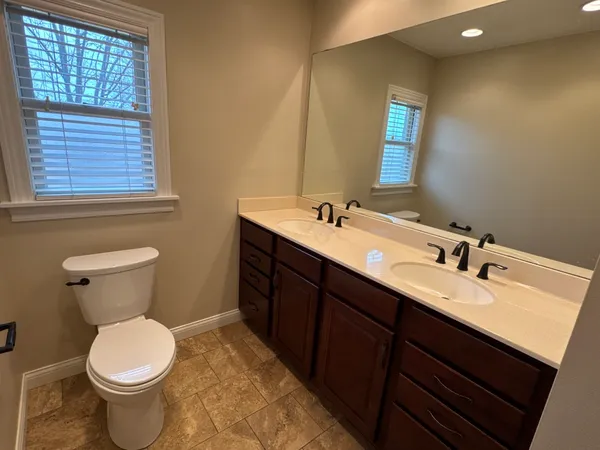 a bathroom with a double vanity sink toilet and mirror