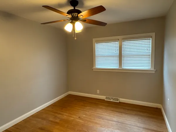 an empty room with a window and a fan