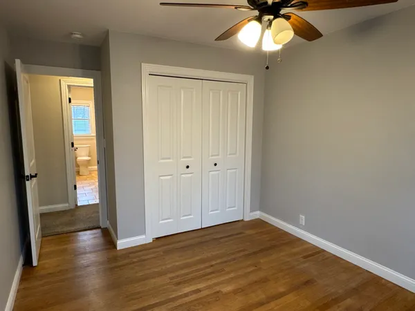 a view of empty room with wooden floor and fan