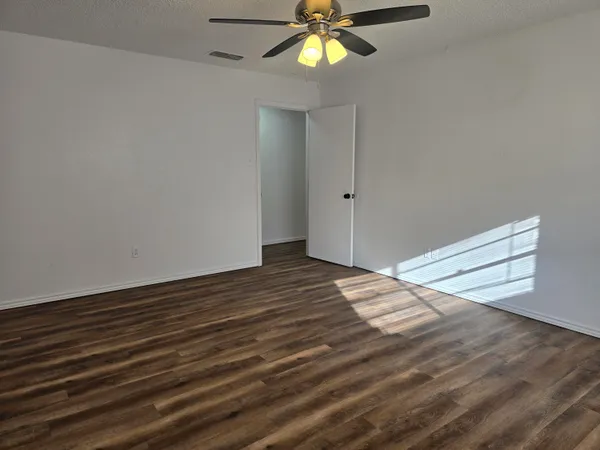 a view of a room with wooden floor and ceiling fan