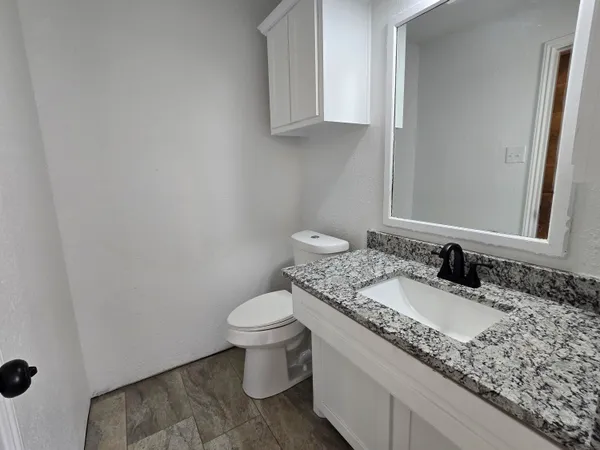 a bathroom with a granite countertop sink and a toilet
