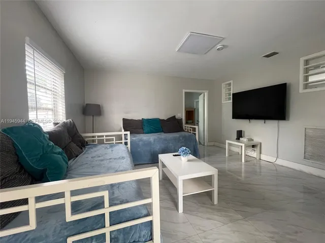 a living room with furniture a flat screen tv and a large window