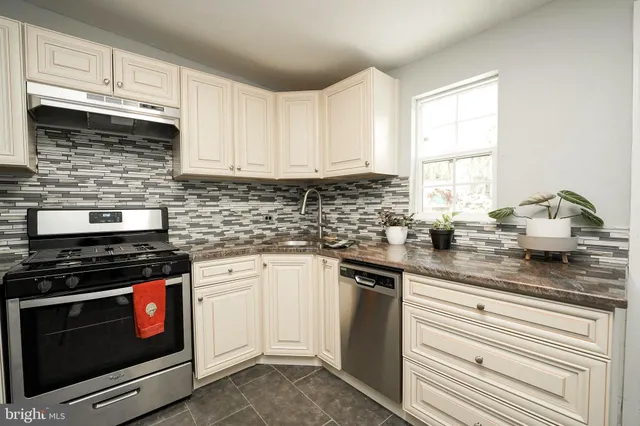 a kitchen with granite countertop a stove sink and cabinets