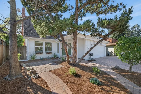 a view of a house with a yard tree and a large tree