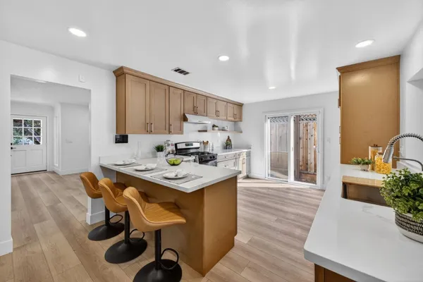 a living room with stainless steel appliances furniture a kitchen view and wooden floor