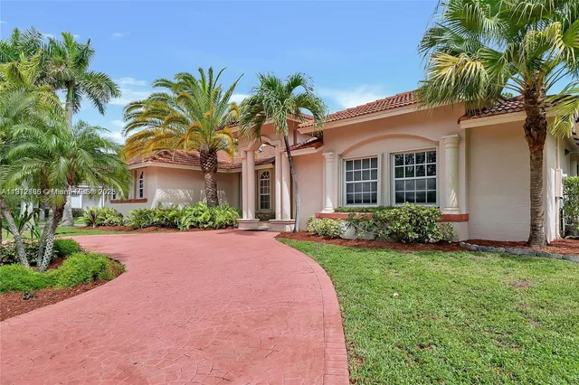 front view of a house with a yard and palm trees