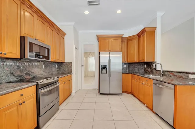 a large kitchen with stainless steel appliances granite countertop a stove top oven a sink and dishwasher