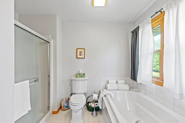 a white bath tub sitting next to a white toilet and a window