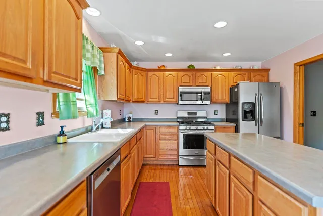a kitchen with stainless steel appliances granite countertop a sink a stove and a refrigerator