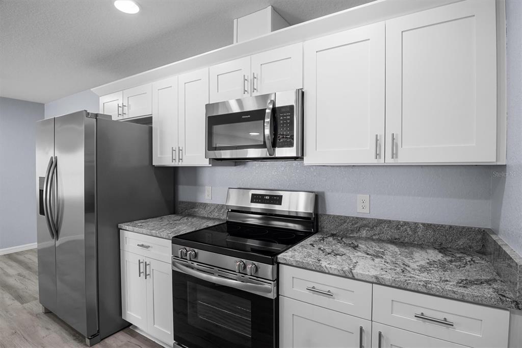 4078 Oak Loop Mulberry, FL 33860 - Photo 8 of 19 a kitchen with stainless steel appliances granite countertop white cabinets a refrigerator a stove a sink and dishwasher