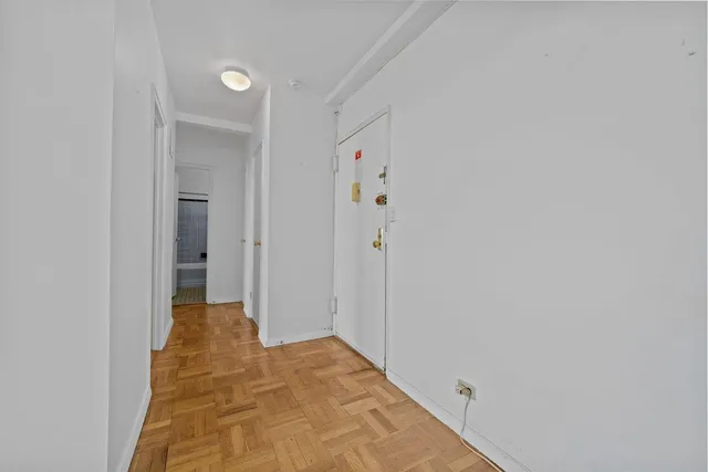a view of a hallway with wooden floor and closet