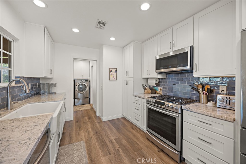7548 Pepper Street Rancho Cucamonga, CA 91730 - Photo 9 of 24 a kitchen with granite countertop a stove top oven a refrigerator a sink and dishwasher with wooden floor
