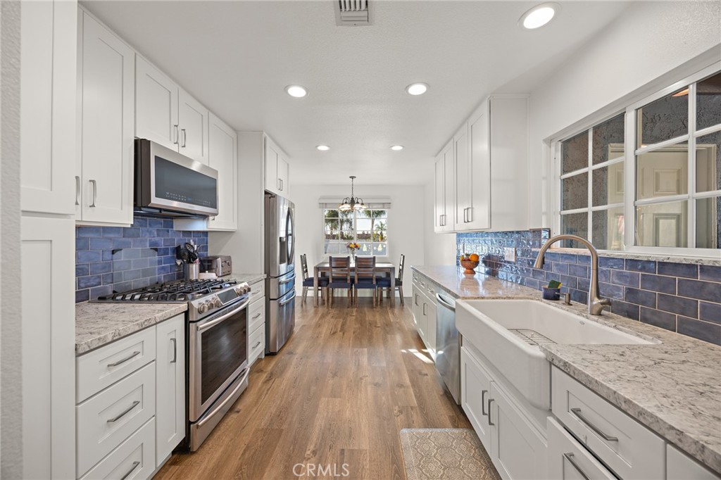 7548 Pepper Street Rancho Cucamonga, CA 91730 - Photo 10 of 24 a kitchen with wooden floors a sink a counter top space stainless steel appliances and cabinets