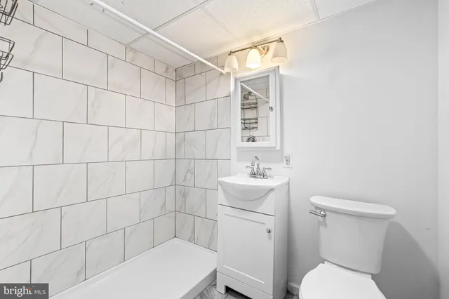 a bathroom with a toilet a sink a mirror and shower
