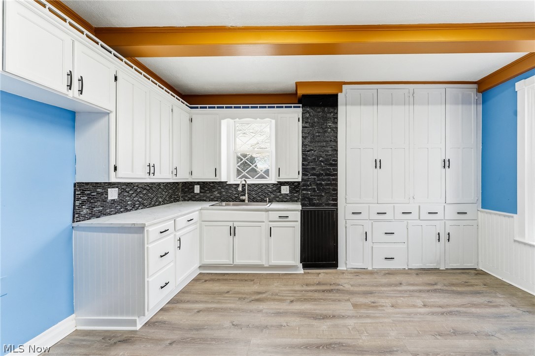 563 Geneva Avenue Struthers, OH 44471 - Photo 5 of 31 Kitchen with white cabinets, light wood-style floors, backsplash, and a wainscoted wall