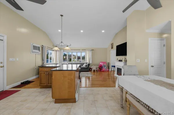 a large living room with stainless steel appliances kitchen island granite countertop a table chairs in it and a flat screen tv