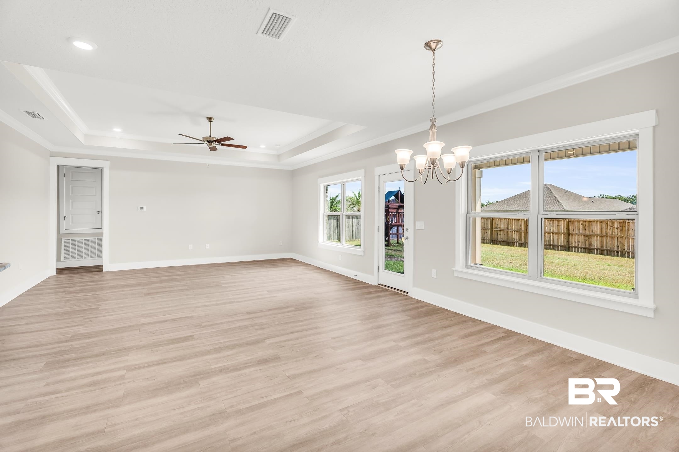 1720 Partridge Street Foley, AL 36535 - Photo 13 of 32 Spare room featuring light hardwood / wood-style floors, a raised ceiling, ceiling fan with notable chandelier, and plenty of natural light