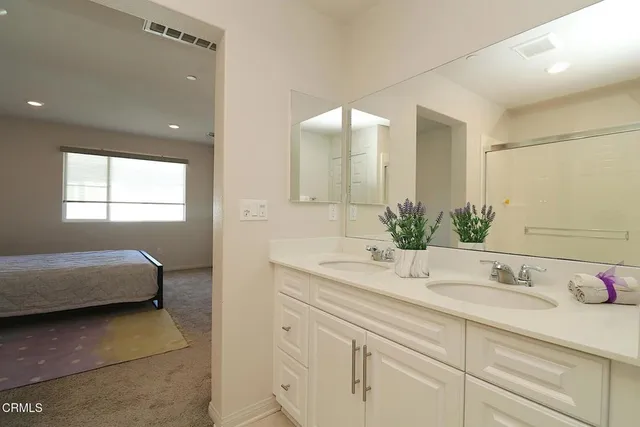 a en suite bathroom with a granite countertop sink a mirror and a shower