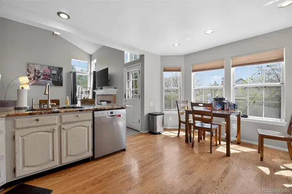 a open dining room with kitchen island granite countertop wooden floor and a view of living room