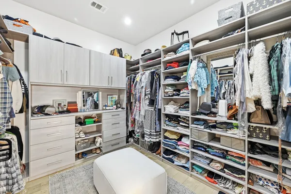 a view of walk in closet with clothes and shoes