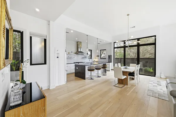 a living room with stainless steel appliances furniture a flat screen tv and a large window