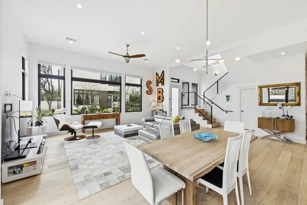 a living room with dining table couches and kitchen view with wooden floor