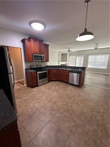 a large kitchen with kitchen island a large counter space a sink a window and stainless steel appliances