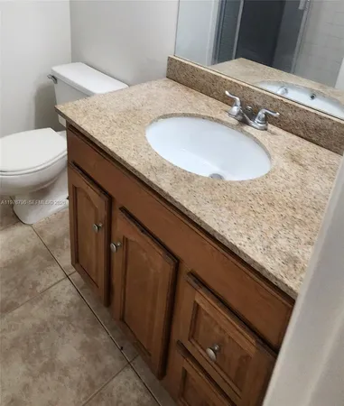 a bathroom with a granite countertop sink and a toilet
