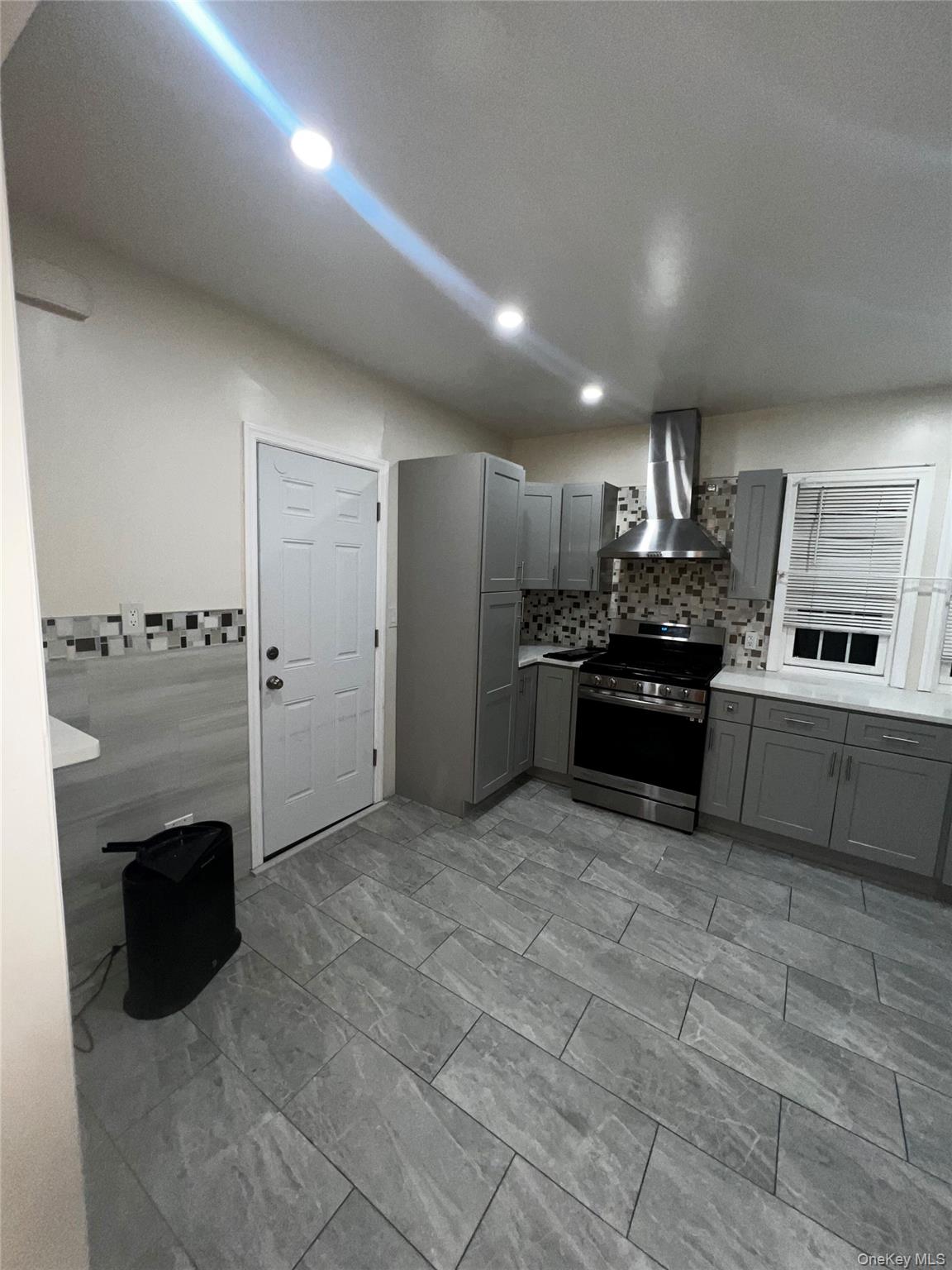 349 Warwick Avenue Mount Vernon, NY 10553 - Photo 5 of 15 Kitchen with gray cabinetry, light countertops, electric range, wall chimney range hood, and recessed lighting