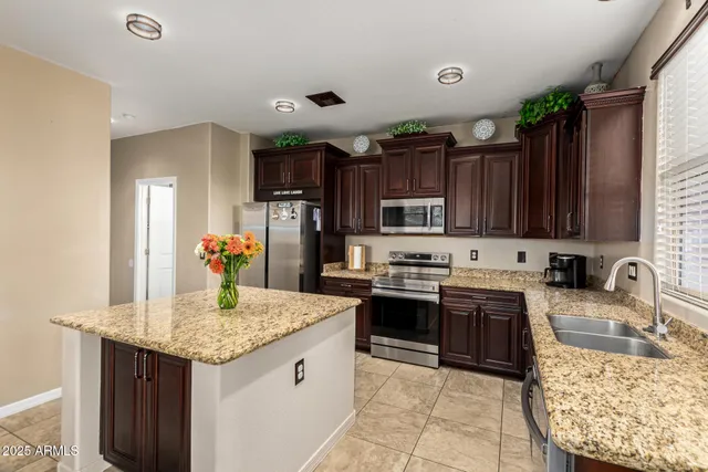 a kitchen with granite countertop stainless steel appliances a sink dishwasher stove refrigerator and cabinets