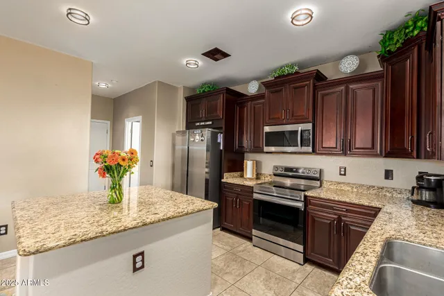 a kitchen with stainless steel appliances granite countertop a refrigerator a stove and a sink
