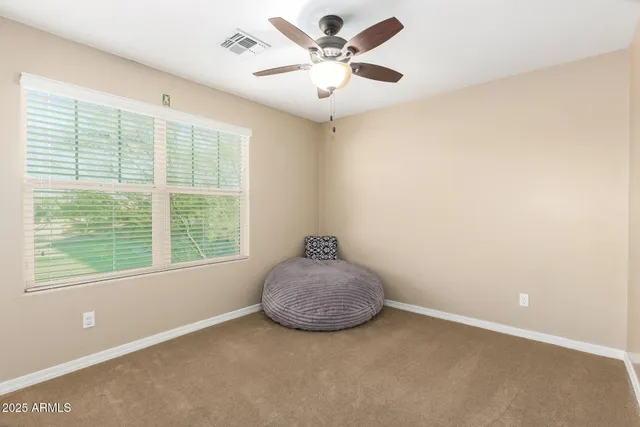 an empty room with chandelier fan and windows