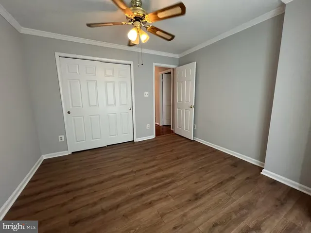 an empty room with wooden floor closet and fan