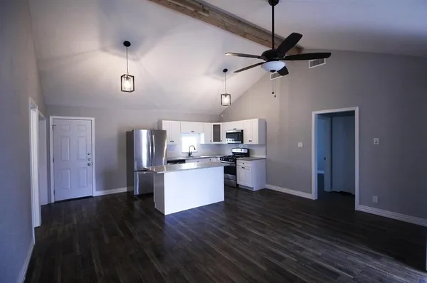 a living room with stainless steel appliances kitchen island hardwood floor and a kitchen view
