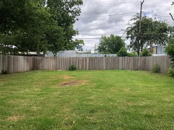 a view of a yard with large trees and wooden fence