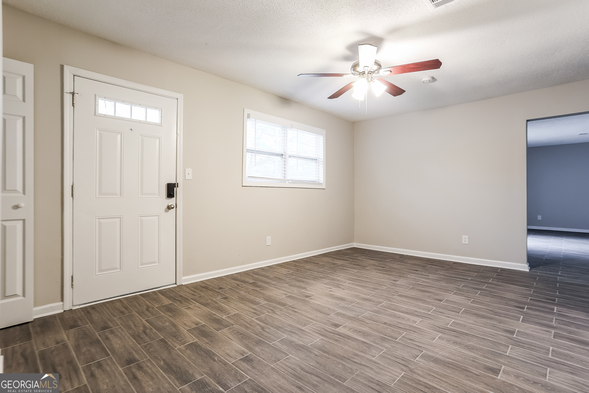 8621 Chestnut Lane Lithia Springs, GA 30122 - Photo 3 of 16 a view of an empty room with wooden floor and a ceiling fan