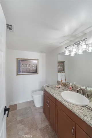 a bathroom with a granite countertop sink mirror vanity and toilet