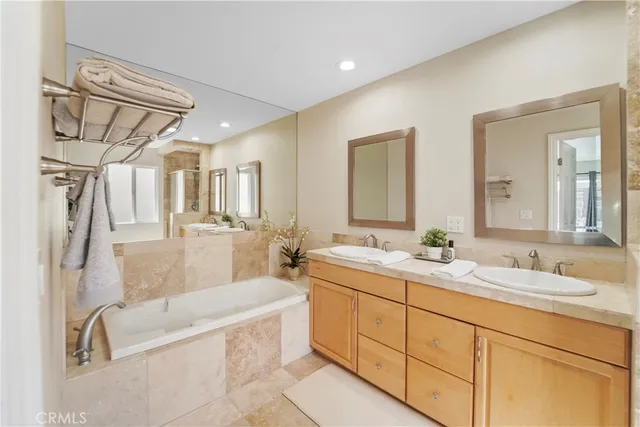 a bathroom with a tub a double vanity sink and mirror