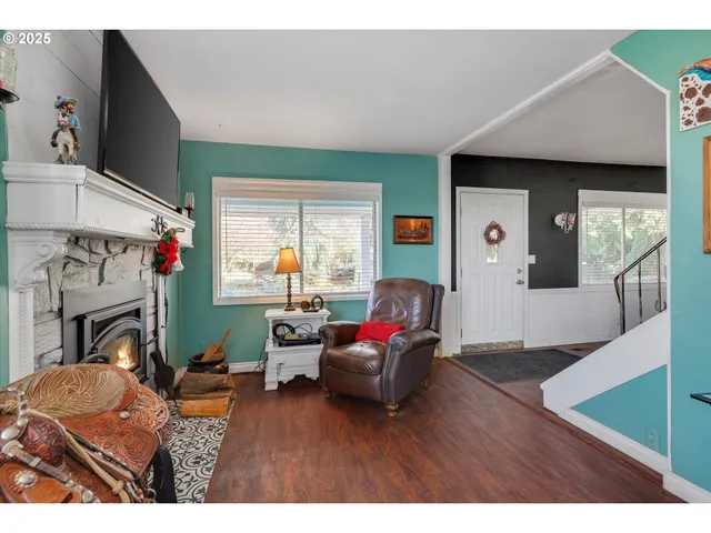 a dining hall with stainless steel appliances granite countertop a refrigerator a stove a dining table and chairs with wooden floor