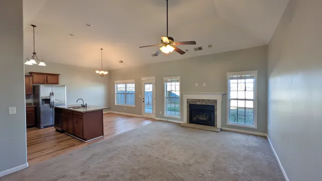 a view of a livingroom with fireplace ceiling fan and windows